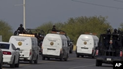 Federal police on vehicles escort the three forensic trucks where bodies were placed after dozens of bodies, some of them mutilated, were found on a highway connecting the northern Mexican metropolis of Monterrey to the U.S. border in the town of San Juan