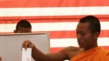 Cambodian Buddhist monk, right, casts his ballot in local elections at Wat Than pagoda's polling station in Phnom Penh, Sunday, June 3, 2012. 