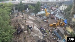 Petugas pemadam kebakaran dan penyelamatan di lokasi gedung roboh di Mumbai (27/9). (AFP/Indranil Mukherjee)