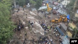 Para petugas pemadam kebakaran dan tim SAR terlihat di sekitar bangunan yang rubuh di Mumbai, 27 September 2013.