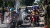 Para petugas menyemprotkan cairan disinfektan kepada para pengendara motor dari Pulau Madura sebelum memasuki Surabaya, Jawa Timur, di tengah wabah virus corona COVID-19, Jumat, 10 April 2020. (Foto: AFP)