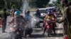 Para petugas menyemprotkan cairan disinfektan kepada para pengendara motor dari Pulau Madura sebelum memasuki Surabaya, Jawa Timur, di tengah perebakan Covid-19. (Foto: AFP)