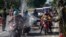 Para petugas menyemprotkan cairan disinfektan kepada para pengendara motor dari Pulau Madura sebelum memasuki Surabaya, Jawa Timur, di tengah perebakan Covid-19. (Foto: AFP)