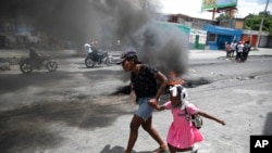 A woman guides a child past a demonstration against increasing violence in Port-au-Prince, Haiti, March 29, 2022.