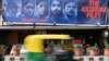 An auto rickshaw moves past a banner of Bollywood movie "The Kashmir Files" installed outside a cinema hall in the old quarters of Delhi, March 21, 2022.
