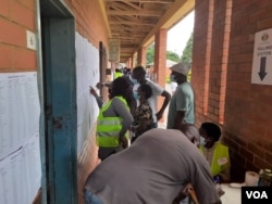 Some Zimbabweans checking their names of a voters' roll outside a polling station in Bulawayo. (VOA)