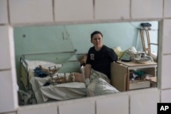 FILE - Natalya Vakula, 44, rests in a hospital in Brovary, on the outskirts of Kyiv, while recovering from injuries after a Russian attack in Chernihiv, Ukraine, March 26, 2022.