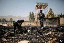 FILE - Yemeni police inspect a site of Saudi-led airstrikes targeting two houses in Sanaa, Yemen, March 26, 2022.