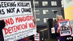 People hold up placards during a pro-refugee rights protest in Melbourne on June 13, 2020.