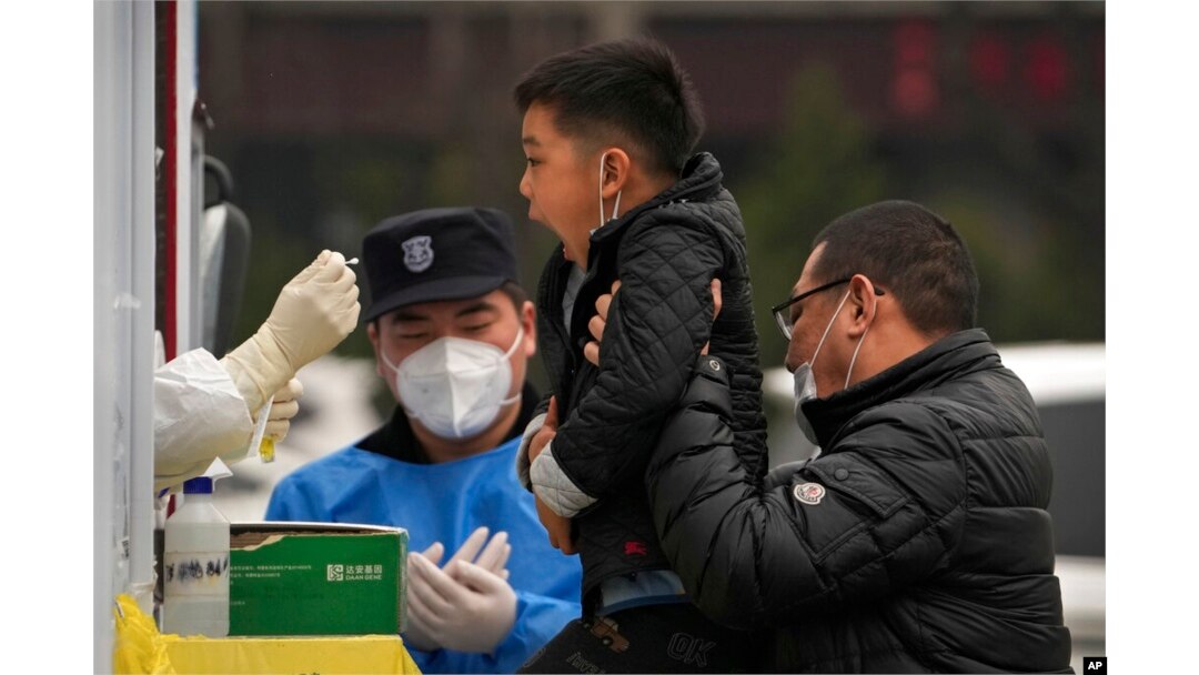 A man lifts his child to get a COVID-19 test at a private mobile coronavirus testing facility, in Beijing, March 29, 2022.