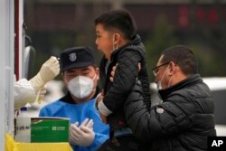 A man lifts his child to get a COVID-19 test at a private mobile coronavirus testing facility, in Beijing, March 29, 2022.
