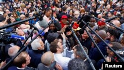 French incumbent president and candidate for the 2022 presidential election&nbsp;Emmanuel Macron carries a girl during a meeting with supporters as he campaigns in Dijon.