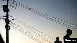 People stand near cables in a suburb of Rio de Janeiro, Brazil March 10, 2022. (REUTERS/Ricardo Moraes)