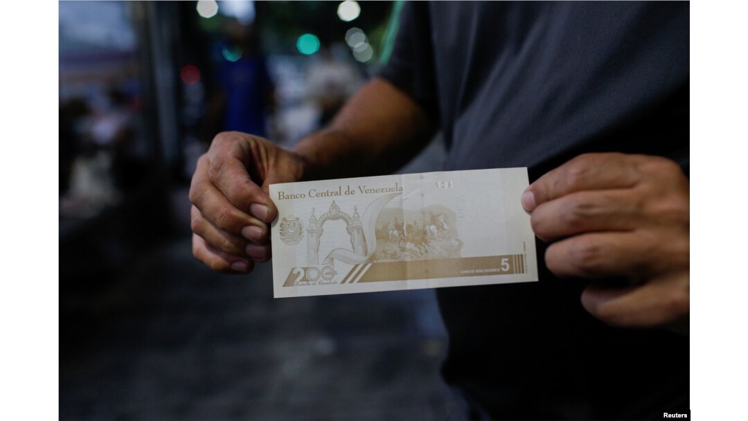 Seorang pria menunjukkan uang kertas baru 5 bolivar di Caracas, Venezuela 1 Oktober 2021. (Foto: REUTERS/Manaure Quintero)