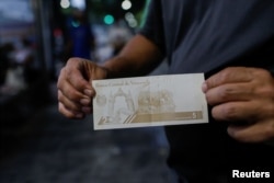 Seorang pria menunjukkan uang kertas baru 5 bolivar di Caracas, Venezuela 1 Oktober 2021. (Foto: REUTERS/Manaure Quintero)