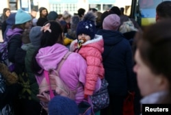 Ukrainian refugees board a bus to take them to a temporary shelter outside Przemysl Glowny train station, after fleeing the Russian invasion of Ukraine, in Przemysl, Poland, March 24, 2022.
