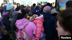 Ukrainian refugees board a bus to take them to a temporary shelter outside Przemysl Glowny train station, after fleeing the Russian invasion of Ukraine, in Przemysl, Poland, March 24, 2022.