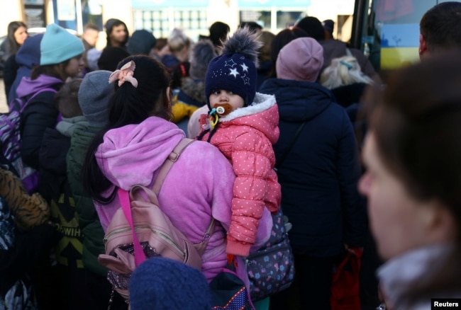 Ukrainian refugees board a bus to take them to a temporary shelter outside Przemysl Glowny train station, after fleeing the Russian invasion of Ukraine, in Przemysl, Poland, March 24, 2022.