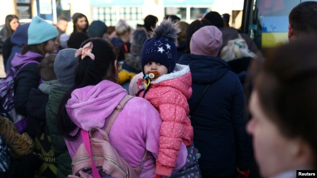 Ukrainian refugees board a bus to take them to a temporary shelter outside Przemysl Glowny train station, after fleeing the Russian invasion of Ukraine, in Przemysl, Poland, March 24, 2022.