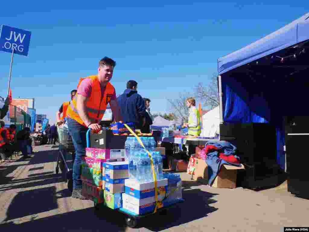 Voluntario transporta diferentes tipos de bebidas de una carpa a otra.