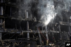 Firefighters try to extinguish a fire amid the destruction caused after shelling of a shopping center, in Kyiv, Ukraine, March 21, 2022.