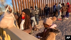 FILE - A Cuban woman and her daughter wait in line to be escorted to a Border Patrol van for processing in Yuma, Ariz., Feb. 6, 2022, hoping to remain in the United States to seek asylum. 