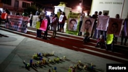 Sejumlah orang memegang foto dari 43 mahasiswa dari Ayotzinapa Teacher Training College Raul Isidro Burgos yang hilang diculik, dalam aksi demonstrasi di Tixtla, di pinggiran Kota Chilpancingo, Meksiko, pada 7 Desember 2014. (Foto: Reuters/Jorge Dan Lopez)