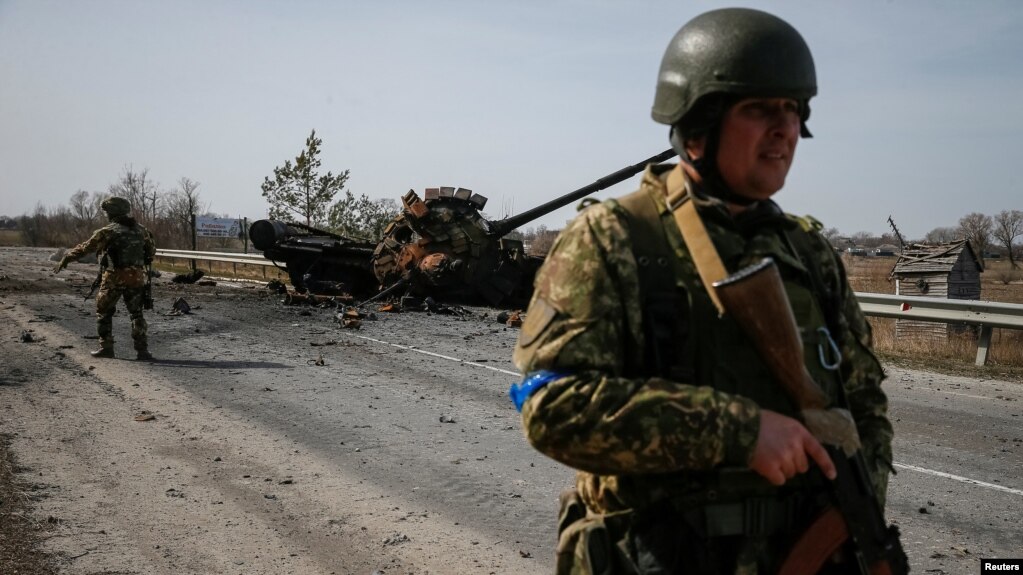 A Ukrainian serviceman stands near the wreck of a Russian tank on the front line in the Kyiv region, Ukraine March 28, 2022. (REUTERS/Gleb Garanich)