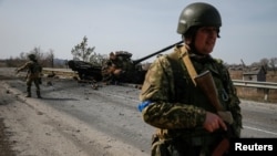 A Ukrainian serviceman stands near the wreck of a Russian tank on the front line in the Kyiv region, Ukraine March 28, 2022. (REUTERS/Gleb Garanich)