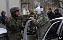 A wounded man talks to a soldier, left, after being evacuated from Irpin, on the outskirts of Kyiv, Ukraine, March 30, 2022.