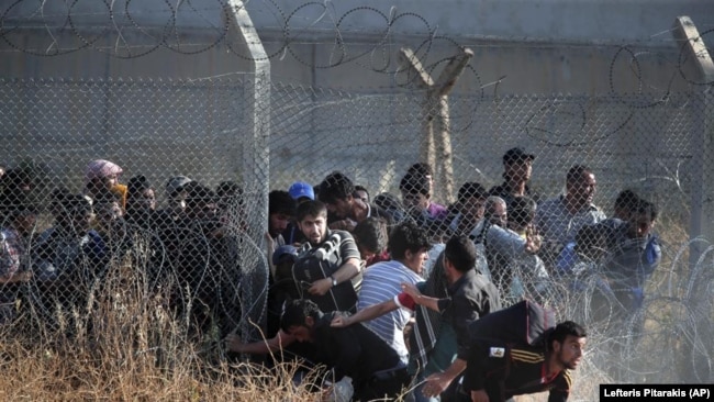 FILE - Syrian refugees cross into Turkey after breaking the border barrier on June 14, 2015. (AP Photo/Lefteris Pitarakis, File)