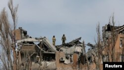지난달 30일 우크라이나 동부 돈바스 지역의 도네츠크 일대에 공습이 단행된 직후 파손된 공동주택을 소방대원들이 살피고 있다. (자료사진)