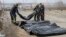 FILE - Ukrainian soldiers collect bodies of civilians killed by the Russian forces at the destroyed bridge in Irpin close to Kyiv, Ukraine, March 31, 2022.