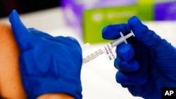 FILE - A health worker administers a dose of a Moderna COVID-19 vaccine during a vaccination clinic at the Norristown Public Health Center in Norristown, Pa., Dec. 7, 2021.