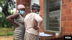 Some women checking their names on the voters' roll outside a polling station in Bulawayo. (VOA)