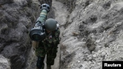 烏克蘭軍人肩扛一枚英國和瑞典研製的NLAW(下一代輕型反坦克武器)導彈發射器，走在基輔地區北部的一處戰壕里。(2022年3月25日)
