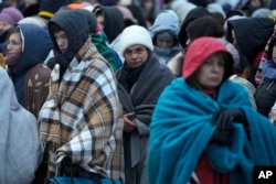 FILE - Refugees, wait in a crowd for transportation after fleeing from the Ukraine and arriving at the border crossing in Medyka, Poland, on March 7, 2022. The U.N. refugee agency says more than 4 million refugees have now fled Ukraine following Russian invasion.