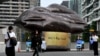 Morning commuters walk past a giant inflatable depicting a piece of coal erected by Greenpeace outside Australian energy company AGL in Melbourne on March 28, 2022. 