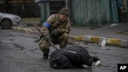 یک نیروی اوکراینی هنگام بررسی جسد یک شهروند کشورش است که آیا قوای روسی در بدنش مواد انفجاری را جاسازی کرده است یا خیر