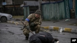 乌克兰军人在基辅郊区之前被俄罗斯军队占领的地区检查死难平民身上是否有诱杀装置（2022年4月2日）