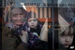 FILE - Internally displaced people look out from a bus at a refugee center in Zaporizhia, Ukraine, on March 25, 2022.