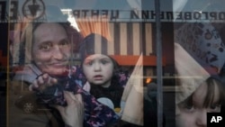 FILE - Internally displaced people look out from a bus at a refugee center in Zaporizhia, Ukraine, on March 25, 2022.