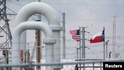 Bendera Amerika Serikat dan negara bagian Texas berkibar di latar belakang Labirin pipa minyak mentah dan peralatan di Cadangan Minyak Strategis di Freeport, Texas, AS, 9 Juni 2016. (REUTERS/Richard Foto Carson/File)