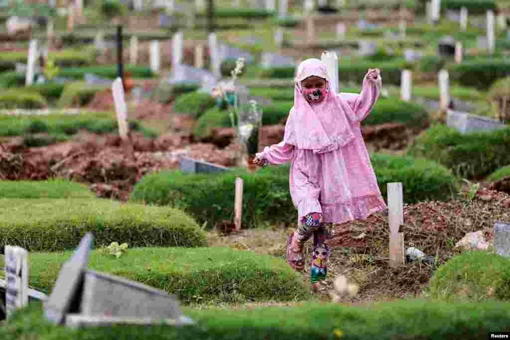 A Muslim girl visits the grave of her relative, who passed away last year due to COVID-19, at the Rorotan cemetery complex in Jakarta, Indonesia.