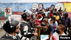 Migrantes hacen cola junto a miembros de la Guardia Nacional, para ser procesados por visas humanitarias para continuar su viaje hacia Estados Unidos, afuera de la oficina del Instituto Nacional de Migración (INM) en Tapachula, México, el 24 de febrero de 2022.