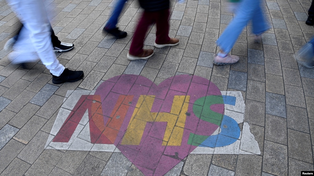 FILE - Shoppers walk past artwork denoting appreciation for the U.K. National Health Service, on Oxford Street in London, Oct. 20, 2021