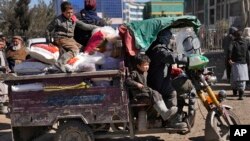 An Afghan man with his children ride in a three-wheeled vehicle after they received food supplies, during a distribution of humanitarian aid for families in need, in Kabul, Afghanistan, Feb. 16, 2022.