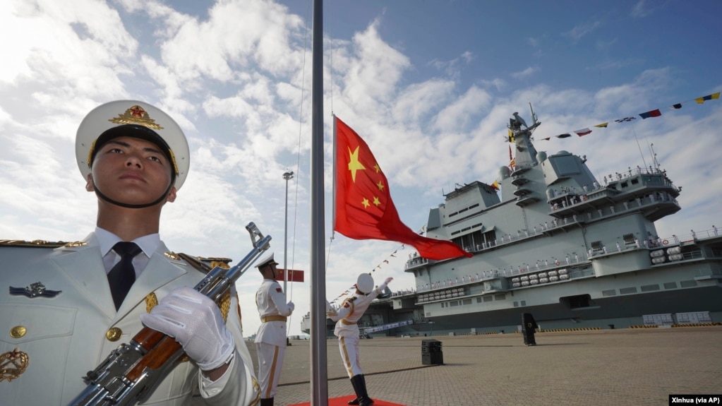 中国航母山东号停泊在海南省的一个海军基地，士兵在举行升旗仪式。（2019年12月17日）(photo:VOA)