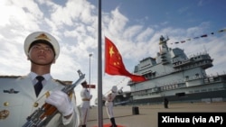 Pengibaran bendera nasional China saat upacara peresmian kapal induk Shandong China di Sanya. Kementerian Luar Negeri China, Rabu (21/9), memperingatkan bahwa kerja sama pertahanan di antara negara-negara "tidak boleh diarahkan ke pihak ketiga." (Foto: Xinhua via AP)