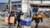 FILE - Local residents carry water from the food warehouse, on the territory which is under the Government of the Donetsk People's Republic control, on the outskirts of Mariupol, Ukraine, March 18, 2022. 